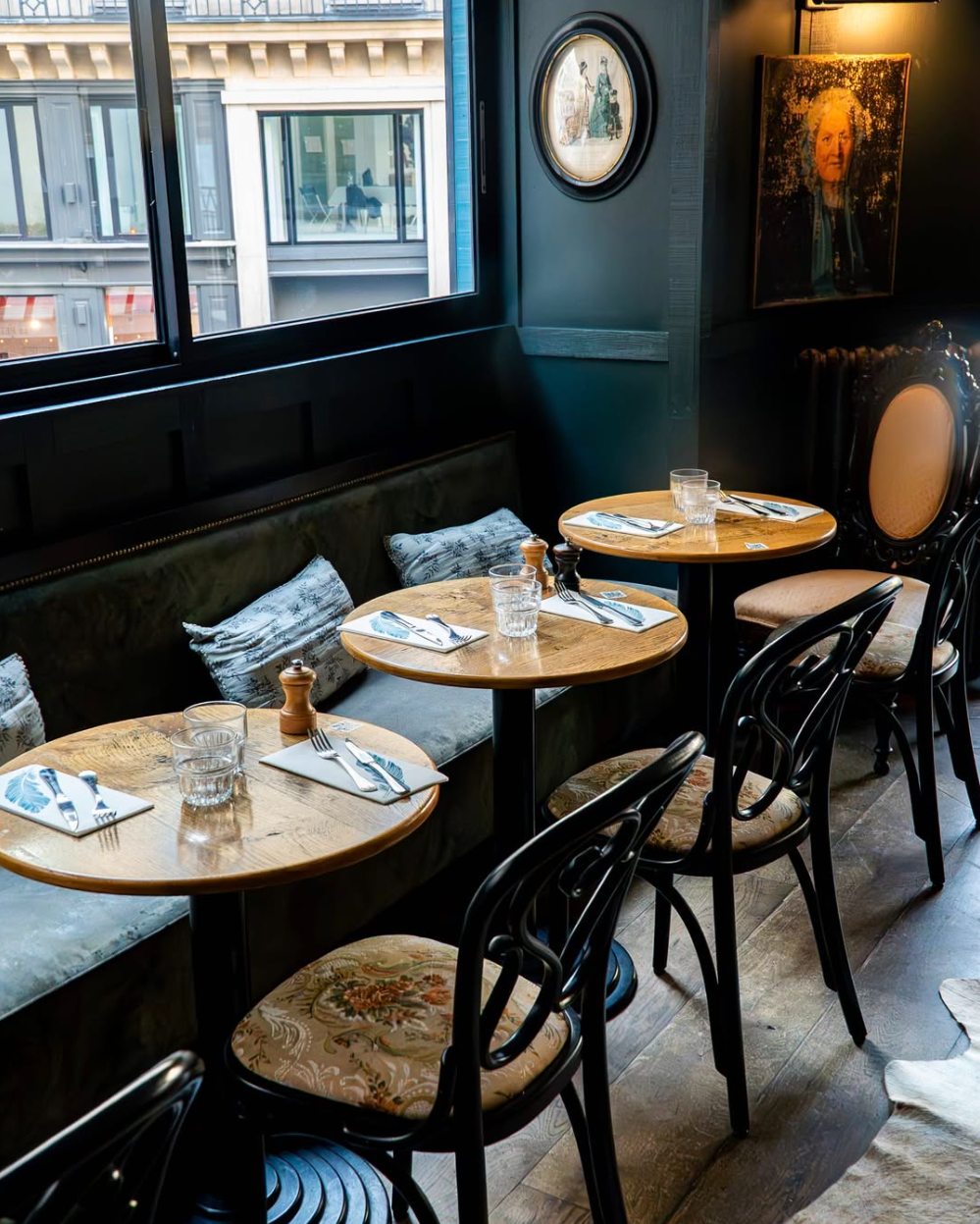 Le salon de l'étage : banquette de velours vert, guéridons en bois, chaises bistrot et fenêtre sur la rue Saint-Honoré